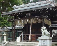 Lion statues guarding the doorway to a shrine, with rock lanterns and ceremonial report streamers noticeable